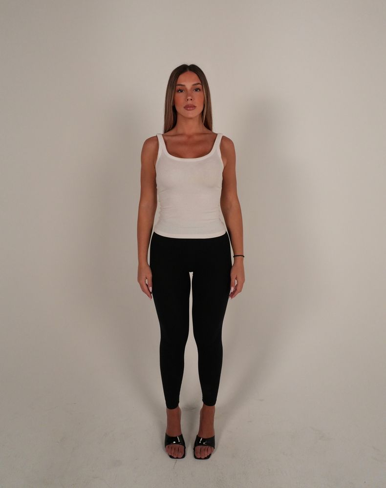 Digital: full-length front view of Sara in a white tank top and black leggings