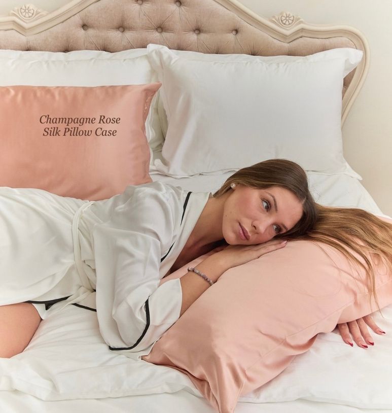 Sara lying on a champagne rose silk pillowcase in a bedding campaign